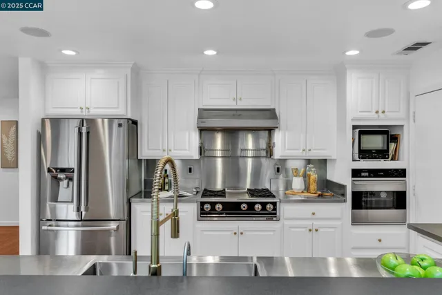 a kitchen with stainless steel appliances kitchen island granite countertop a refrigerator and a stove top oven