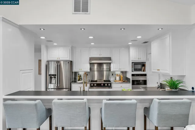 a kitchen with stainless steel appliances a sink a stove a refrigerator and cabinets