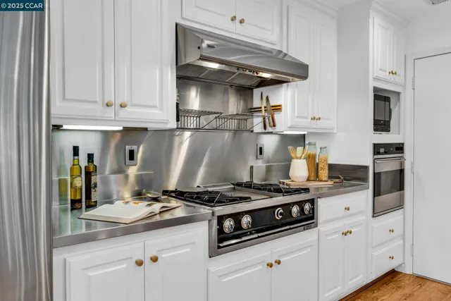 a kitchen with stainless steel appliances granite countertop a stove and a white cabinets