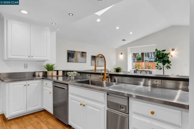 a kitchen with granite countertop a sink stainless steel appliances and white cabinets