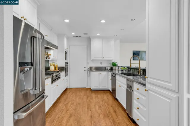 a kitchen with stainless steel appliances a refrigerator sink and white cabinets