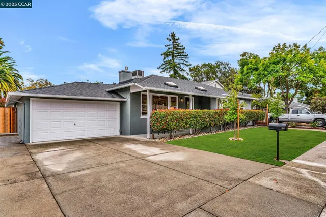 a front view of a house with a garden and trees