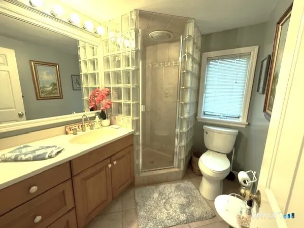 a bathroom with a granite countertop sink toilet a mirror and shower