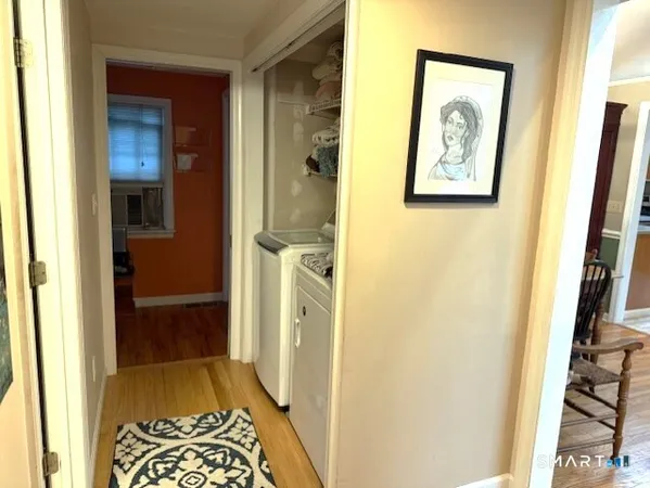 a view of a hallway with wooden floor and a bathroom