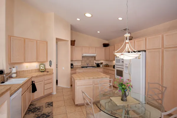a kitchen with a white cabinets and couches with wooden floor