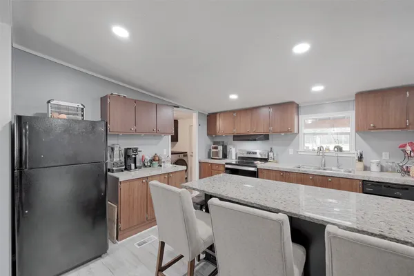 a large living room with stainless steel appliances furniture a couch and a view of kitchen