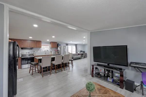 a kitchen with granite countertop a refrigerator a sink a stove a dining table and chairs