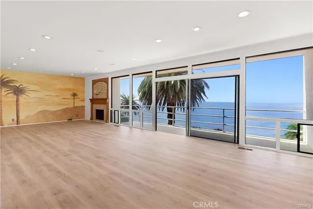 a view of an empty room with wooden floor and windows