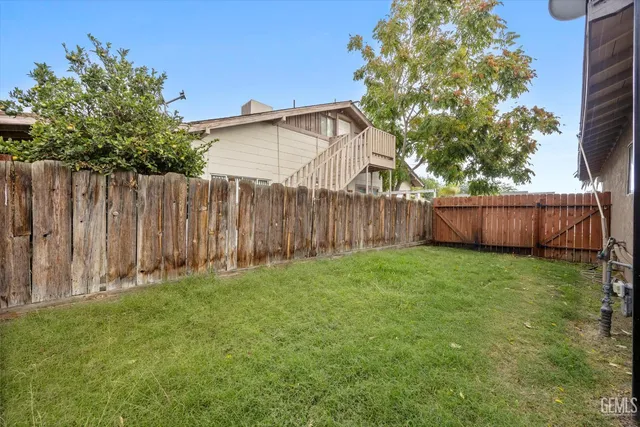 a view of backyard with wooden fence and a large tree