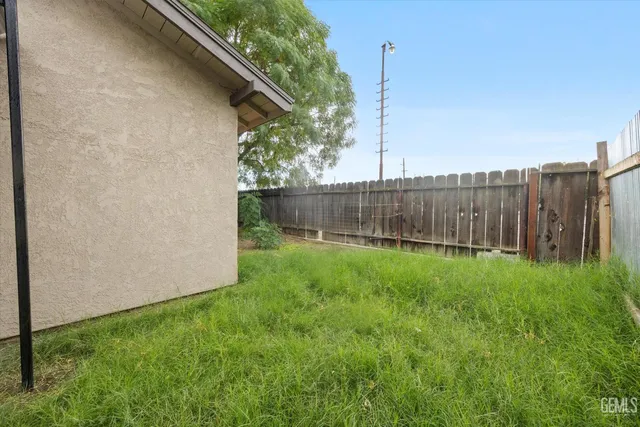 a view of a backyard with plants and wooden fence