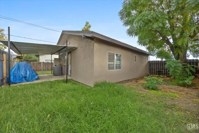 a view of a backyard with plants and large tree