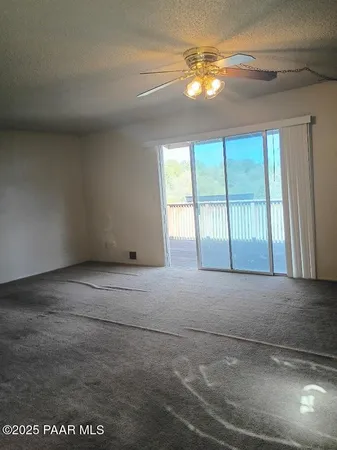 a view of an empty room with chandelier fan and fire place