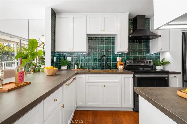 a kitchen with stainless steel appliances granite countertop a sink a stove and a wooden floors