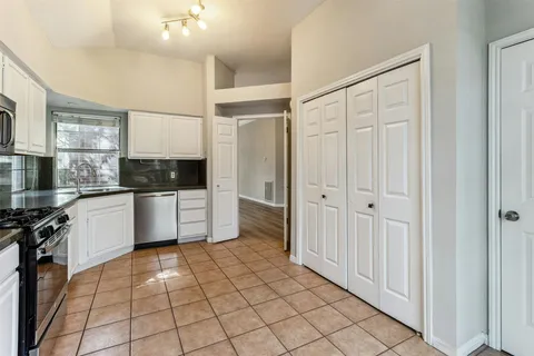 a large white kitchen with a sink stainless steel appliances and cabinets