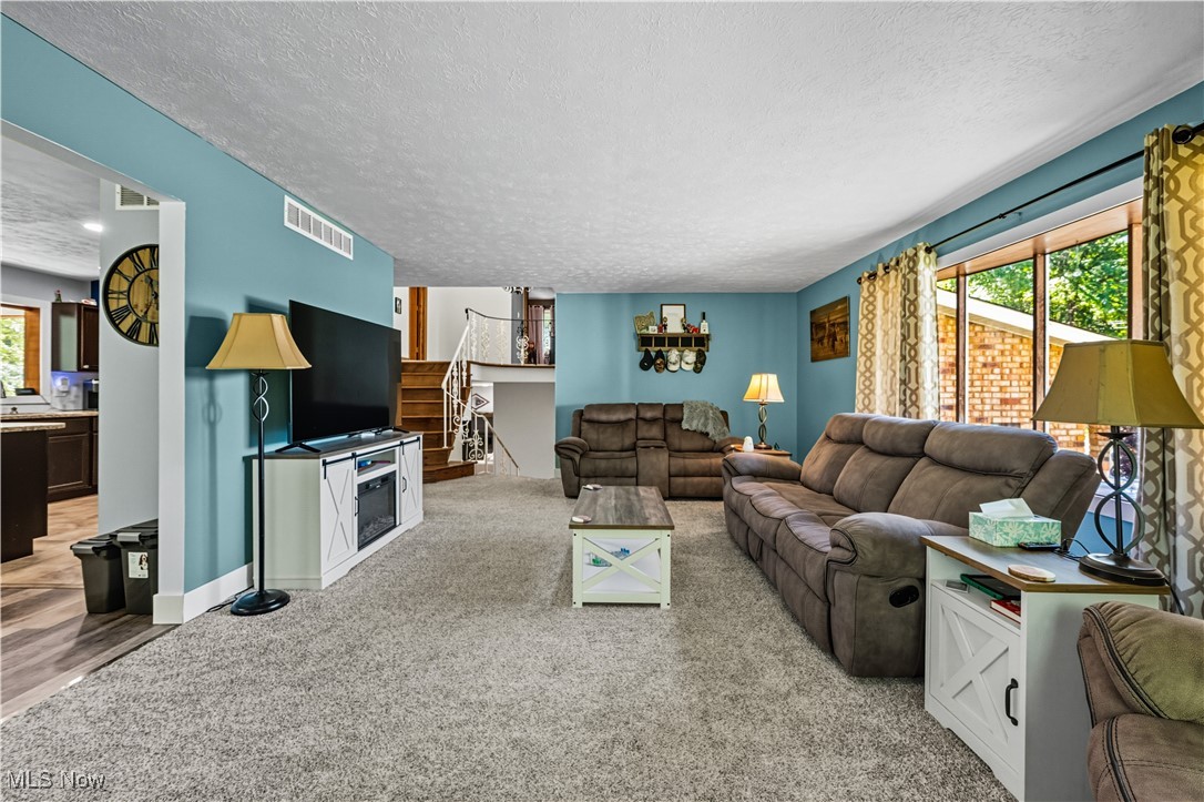 8193 Hartman Road Wadsworth, OH 44281 - Photo 14 of 50 Living room with a textured ceiling, light carpet, and stairway