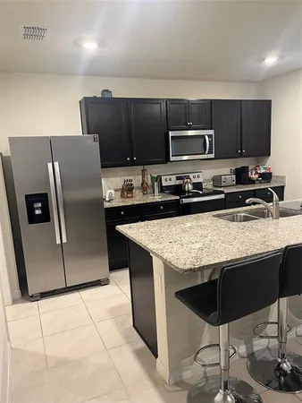 a kitchen with stainless steel appliances granite countertop a stove a refrigerator a sink a microwave and a refrigerator