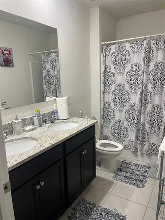 a bathroom with a granite countertop toilet sink and mirror