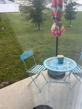 a table and chairs sitting on a pier next to a yard