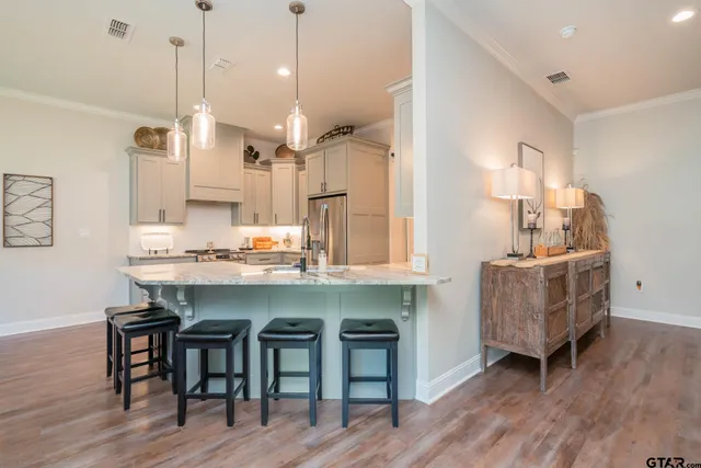 a kitchen with kitchen island stainless steel appliances a table chairs sink and wooden floor