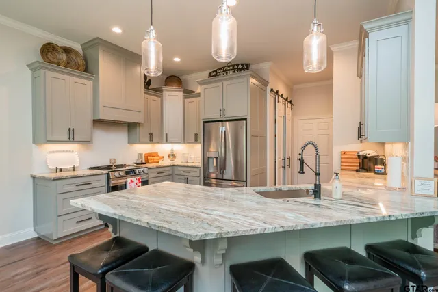 a kitchen with stainless steel appliances granite countertop a table chairs stove and refrigerator