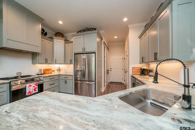 a kitchen with granite countertop a sink stainless steel appliances and cabinets