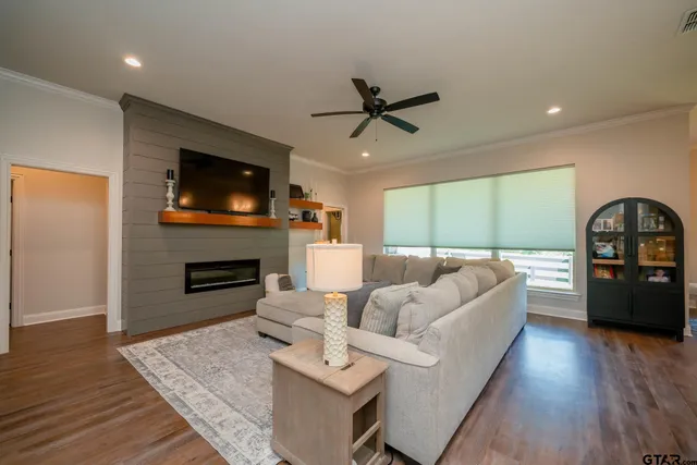 a living room with furniture a fireplace a flat screen tv and kitchen view