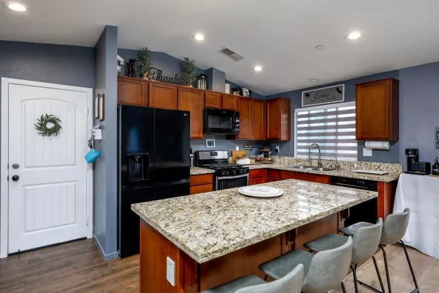 a kitchen with granite countertop kitchen island stainless steel appliances a refrigerator sink and stove