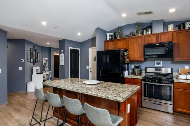 a kitchen with stainless steel appliances granite countertop a stove a refrigerator a kitchen island a sink and chairs