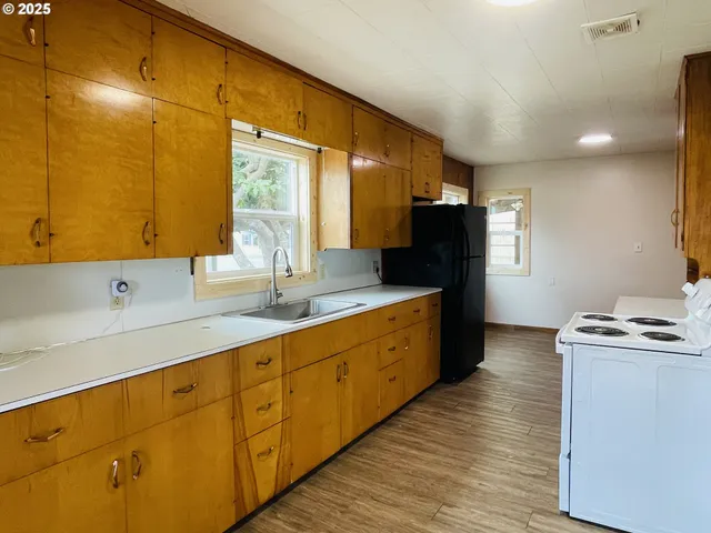 a kitchen with stainless steel appliances a sink cabinets and wooden floor