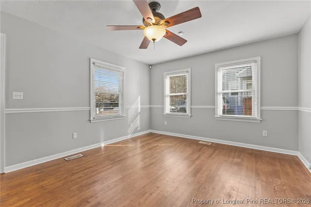 a view of an empty room with window and wooden floor