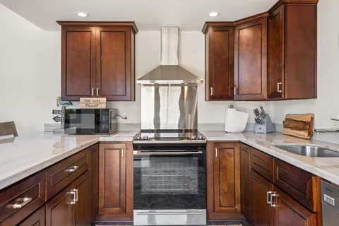 a kitchen with stainless steel appliances granite countertop a stove a sink dishwasher and a refrigerator with wooden floor