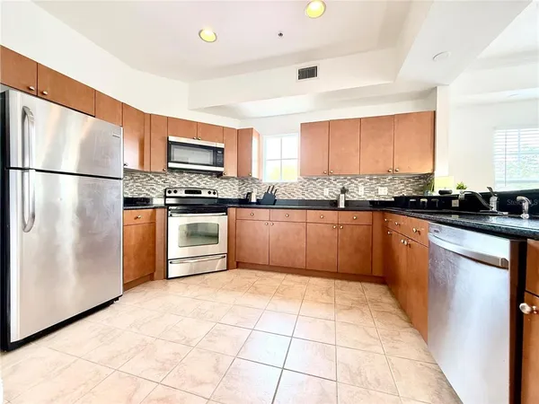 a kitchen with stainless steel appliances granite countertop a stove a sink dishwasher and a refrigerator