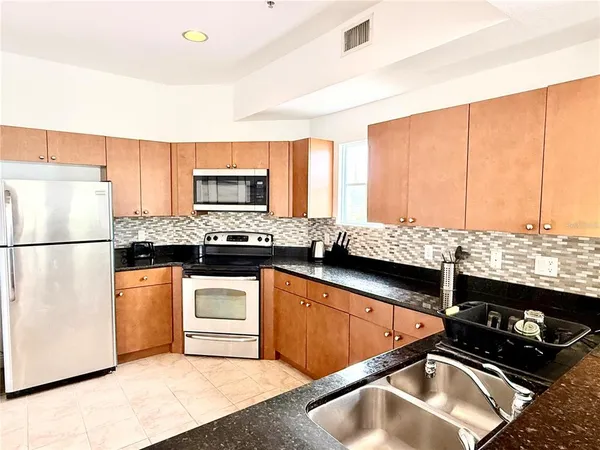a kitchen with stainless steel appliances granite countertop a sink stove and refrigerator