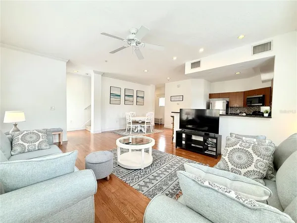 a living room with furniture and a flat screen tv with kitchen view