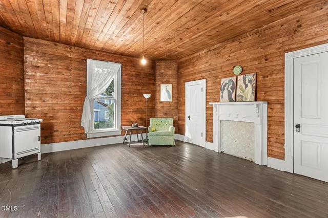 a view of a hallway to a livingroom with wooden floor and stairs