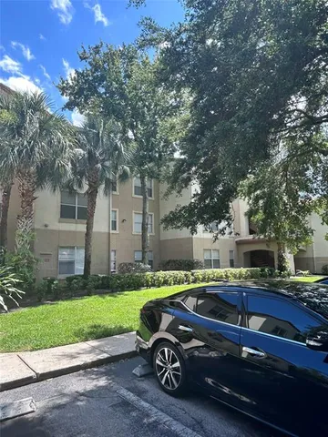 a car parked in front of a brick house with large trees