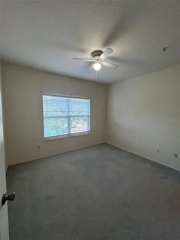 an empty room with a window and a fan