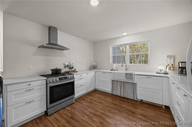 a kitchen with cabinets wooden floor and stainless steel appliances