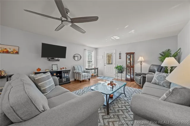 a living room with furniture a clock and a flat screen tv