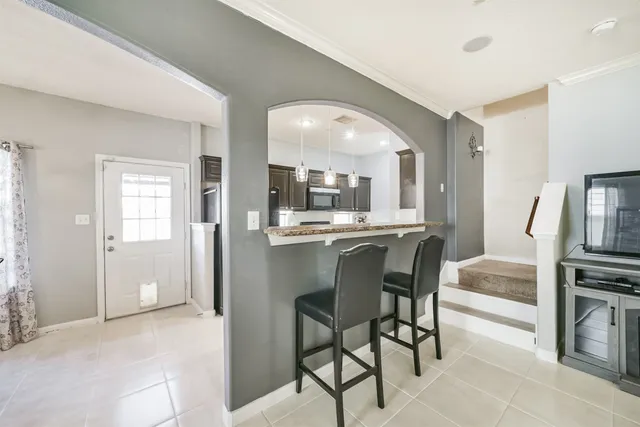 a dining hall with stainless steel appliances kitchen island granite countertop a refrigerator and cabinets