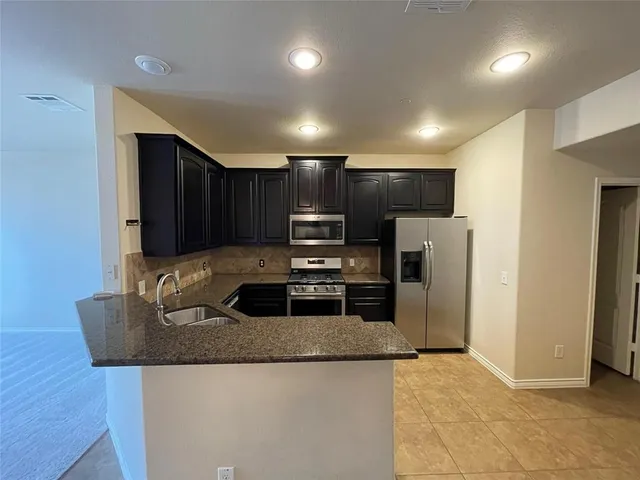a kitchen with granite countertop a refrigerator and a sink