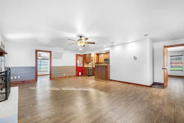 a view of an empty room with wooden floor and a window