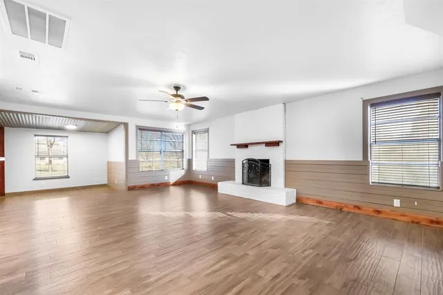 an empty room with wooden floor fireplace and windows