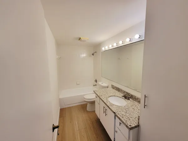 a bathroom with a granite countertop sink mirror vanity and toilet
