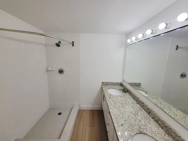 a bathroom with a granite countertop sink a shower and vanity