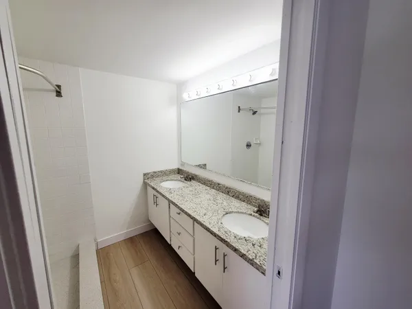 a bathroom with a granite countertop sink a mirror and a shower