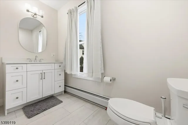 a bathroom with a toilet a sink a mirror and a window