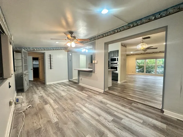 a room with stainless steel appliances wooden floors and large window