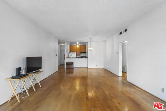a view of room with wooden floor flat screen tv and windows