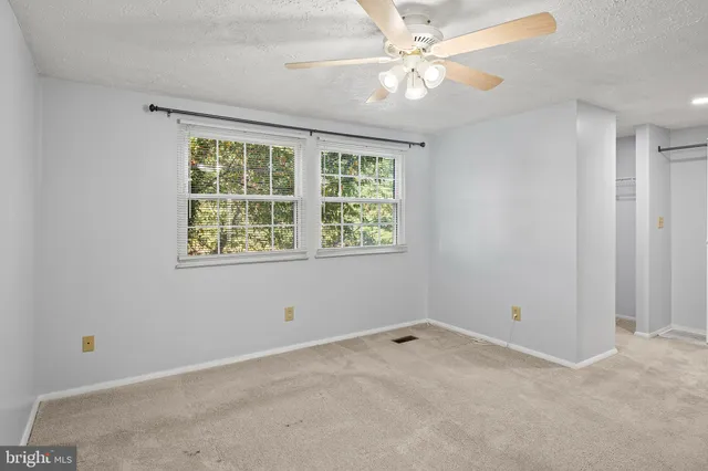 an empty room with windows and fan